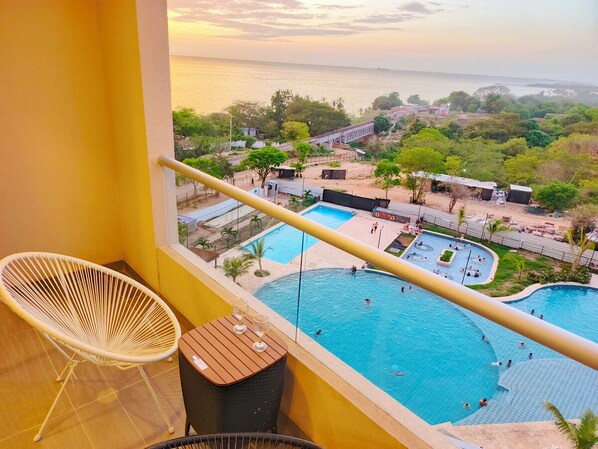 Ein Balkon mit Blick auf einen Swimmingpool und das Meer.