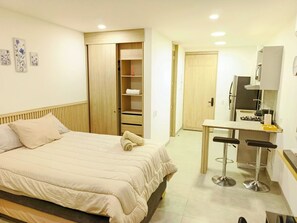 Ein Schlafzimmer mit Bett, Schrank, Küchenzeile und Bad.