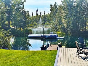 A serene outdoor area with a wooden deck, a floating dock, and a small inflatable boat. - Mirrored Waters Ranch Cabin (Mirror)