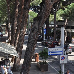 Une scène de rue avec des arbres, des voitures garées et un panneau indiquant « Poncellei » sur la gauche.