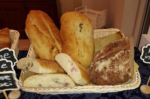 Un panier contenant divers types de pain, notamment des baguettes et un pain fourré dont on peut voir la garniture.