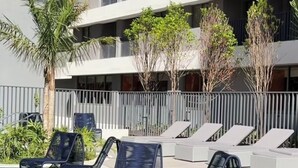 A modern hotel with a pool area, sun loungers, and a multi-story building with balconies. - Luxurious 1-bedroom apartment in Pinheiros. AC, gym, pool, prime location (São Paulo)