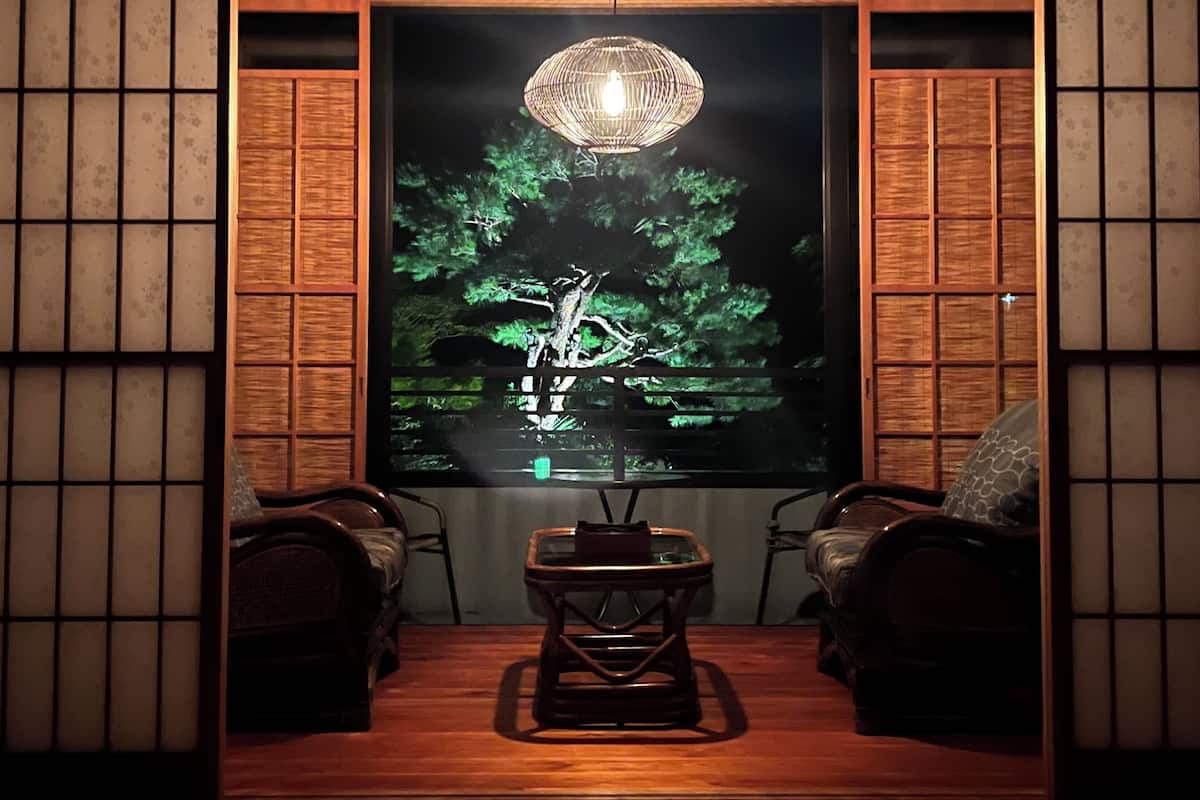 A traditional Japanese-style room with tatami flooring, a low table, and two chairs.