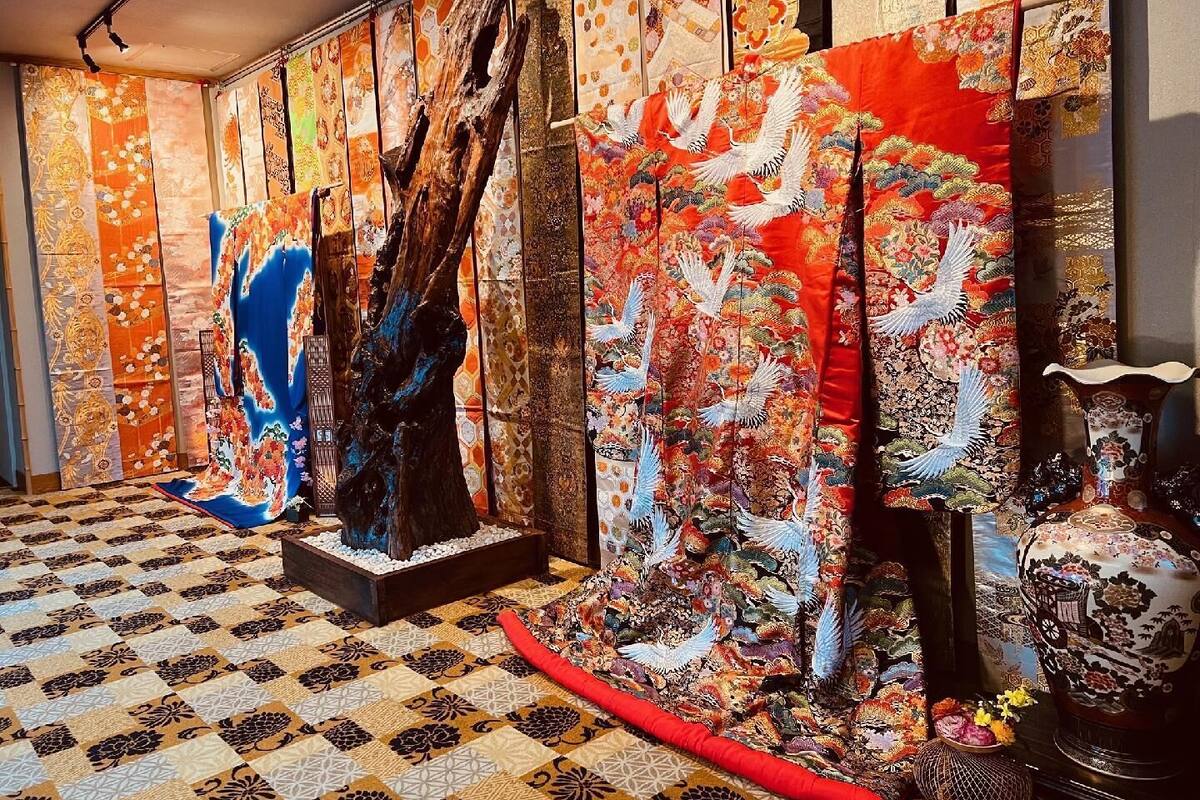 A room with a patterned floor, a large wooden sculpture, and traditional Japanese textiles.