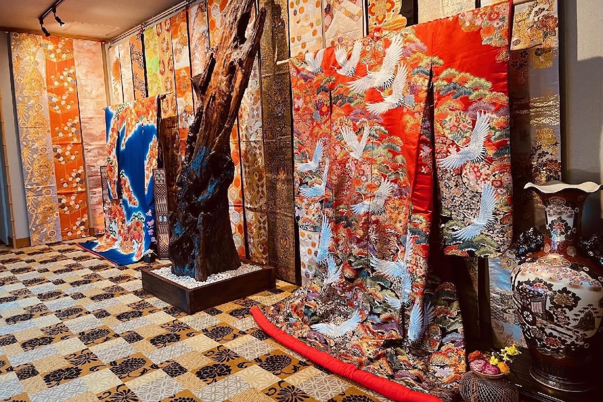 A room with a patterned floor, a large wooden sculpture, and traditional Japanese textiles.