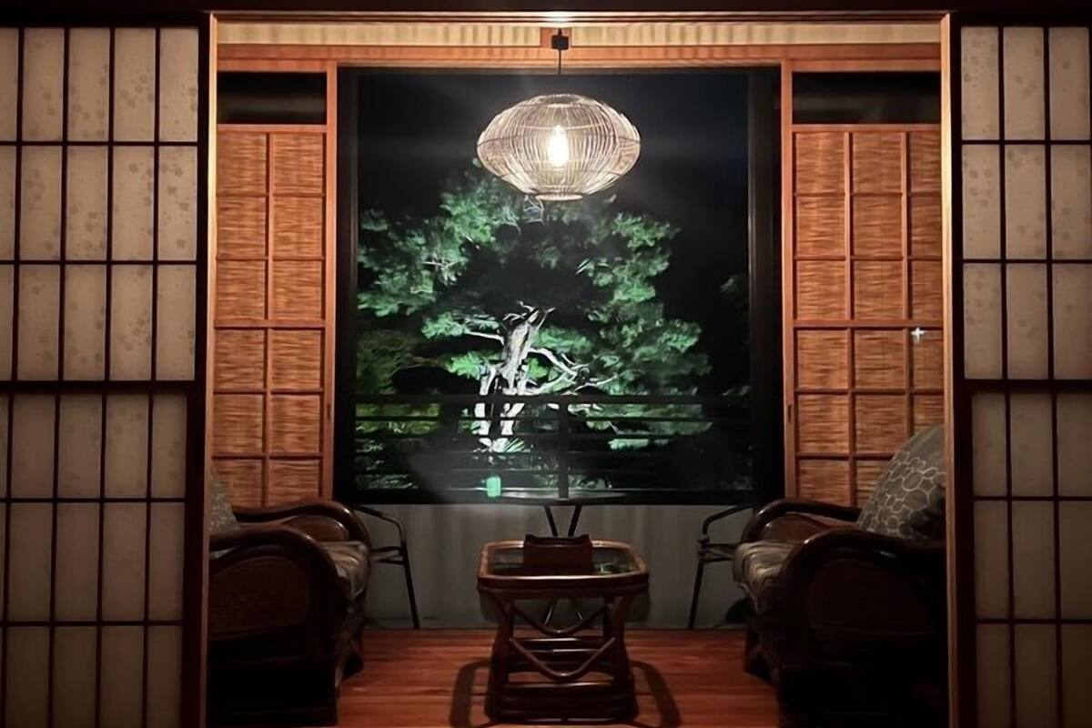 A traditional room with tatami flooring, a low table, and a hanging lamp.