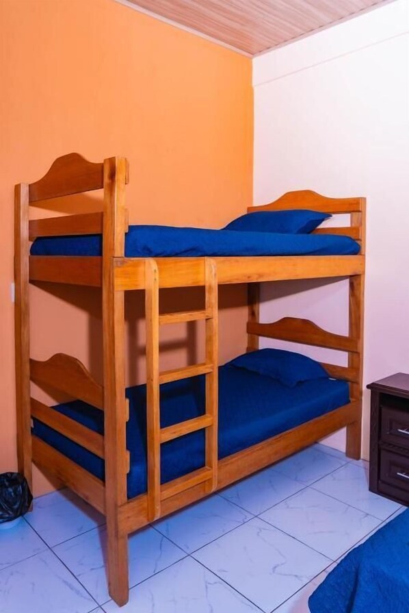 Ein Etagenbett mit drei Schlafstellen, einem Holzkopfstück und blauer Bettwäsche.