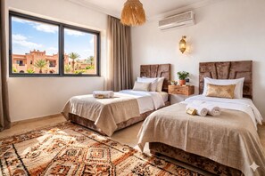 Une chambre d’hôtel avec deux lits, un tapis à motifs, une vue sur les bâtiments environnants et un luminaire suspendu.