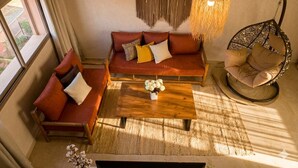 A cozy living room with a sofa, a round chair, a hanging light fixture, and a coffee table. - Bohemian chic in the heart of the red city with swimming pool (Marrakech-Safi)
