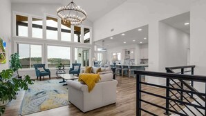 Ein geräumiger Wohnbereich mit einem weißen Sofa, einem blauen Sessel und einem großen Fenster.