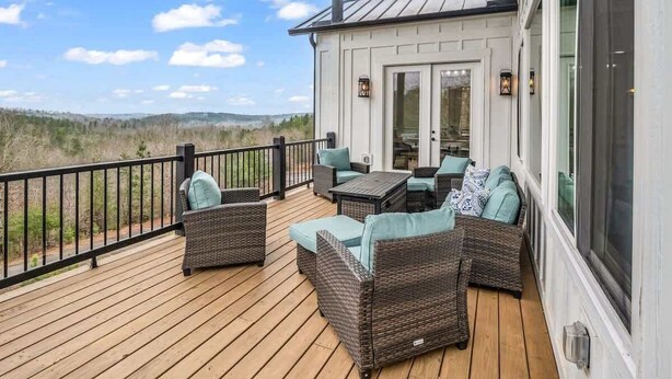 Eine überdachte Terrasse mit Korbmöbeln und Blick auf die Landschaft.