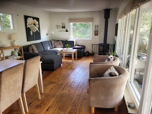 A living room with a sofa, chairs, a coffee table, a fireplace, and a window with a view of greenery.