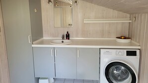 A compact bathroom with a sink, mirror, and washing machine. - Natural plot, fireplace and true west coast (Thisted)