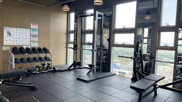 Ein Fitnessraum mit Krafttrainingsgeräten, einer Bank und einem Hantelgestell.