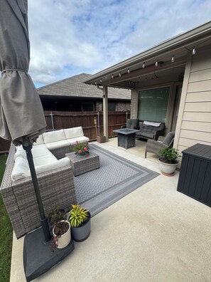 Eine Terrasse mit Gartenmöbeln, einem überdachten Sitzbereich und Topfpflanzen.