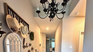 A hallway with a wooden bench, a chandelier, and a welcome sign. - World Cup Ready! Entire Home • Sleeps 8 • 15 Min to Stadium (Fort Worth)