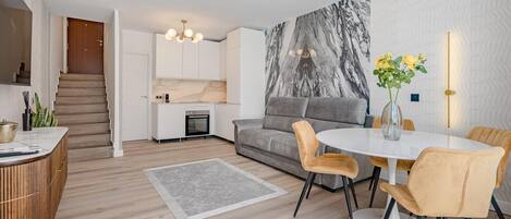Un espacio habitable moderno con cocina, comedor y una escalera que sube a otro nivel.