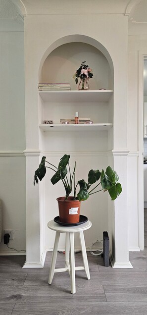 A potted plant on a white pedestal table in a room with a white arched shelf above. - Spacious 2BR Flat, Travellers and Contractors Welcome. Free Parking. (London)