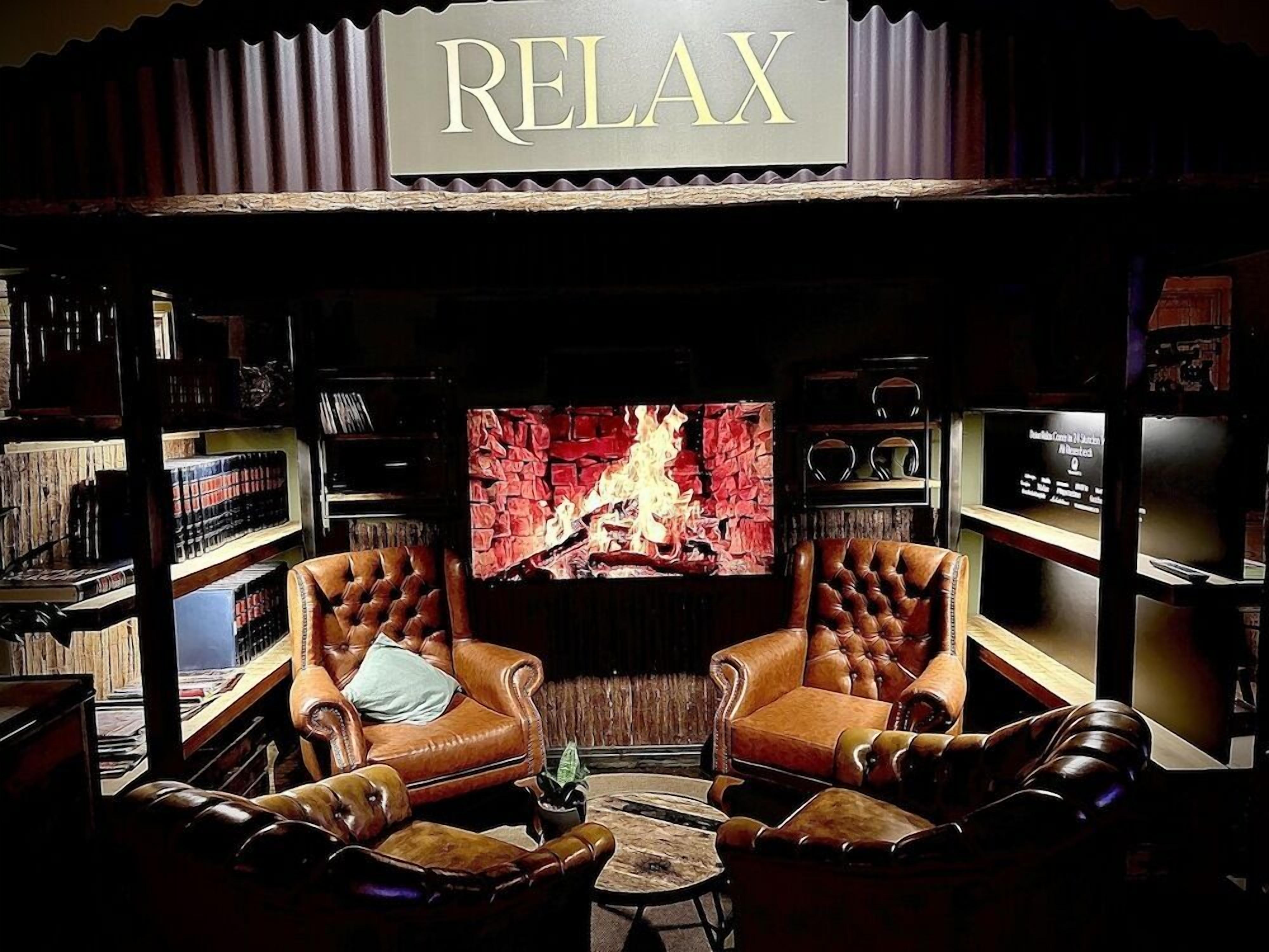 A cozy lounge area with leather armchairs, a fireplace, and bookshelves.