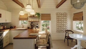 Cozinha com vigas de madeira, luminárias pendentes, ilha central, máquina de café e vista para o exterior.