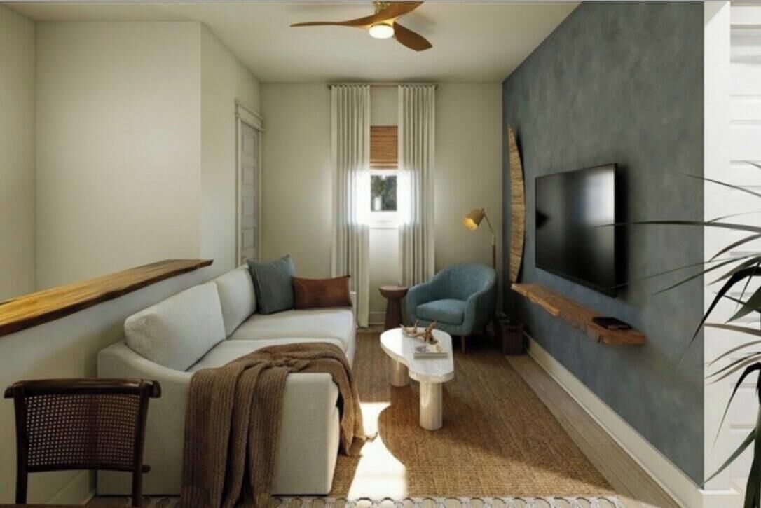 A modern living room with a sofa, armchair, coffee table, and a flat-screen TV mounted on the wall.