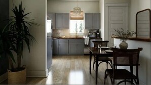 Una cocina moderna con armarios grises, una mesa de comedor de madera y una lámpara colgante.
