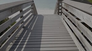 Un muelle de madera que conduce a una playa con una vista despejada del océano.