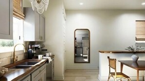Una cocina moderna con una isla central, una araña y vista al área de comedor.
