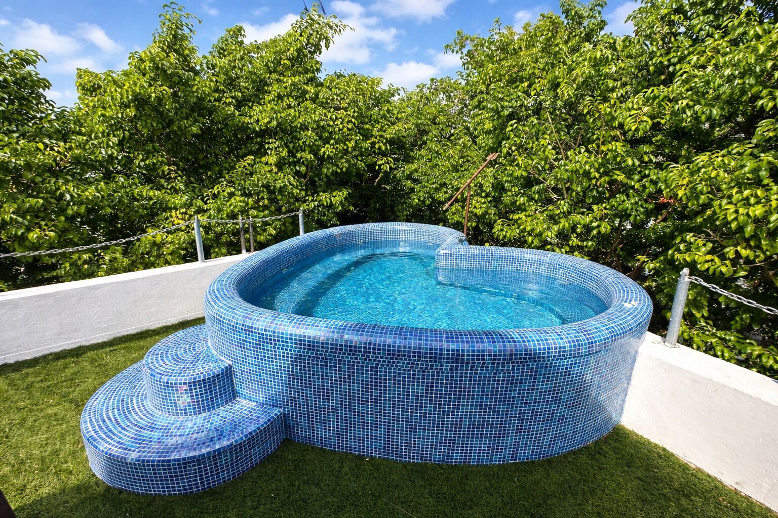 A hot tub with a tiled exterior, surrounded by a grassy area and trees.