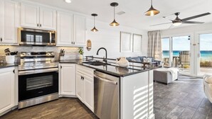 A modern kitchen with white cabinetry, stainless steel appliances, and a large island. - Ground floor unit with rustic flair (Destin)