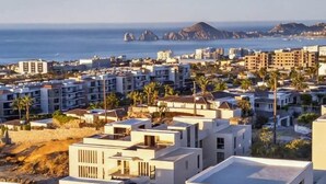 Ein Küstenwohngebiet mit modernen Gebäuden, freiem Blick auf das Meer und einer entfernten Bergkette.