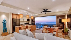 Ein modernes Wohnzimmer mit Sofa, Essbereich, Küche und großem Fenster mit Blick.