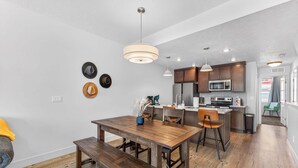 Une cuisine moderne avec un plancher en bois, un coin repas avec une table et des bancs en bois, et un îlot central doté de sièges.