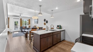 Une cuisine moderne avec des meubles en bois, un grand îlot central et des luminaires suspendus.