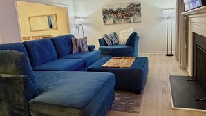 Ein modernes Wohnzimmer mit einer Eckcouch, einer kleinen Couch und einem Flachbildfernseher.