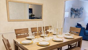 Ein Essbereich mit einem Holztisch, gedeckt für sechs Personen, mit goldenen Akzenten und weißen Kerzen.