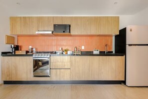Eine moderne Küche mit Holzausstattung, einem Backofen, einer Mikrowelle und einem Kühlschrank.