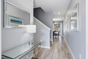 A modern hallway with a glass console table, a staircase, and a dining area in the background. - Orlando Getaway w/ Private Pool & Lazy River (Davenport)
