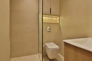 A modern bathroom with a glass-enclosed shower, a white toilet, and a freestanding bathtub. - Luxury Studio with Bathtub Steps to City Stars (Cairo Governorate)