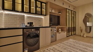 Une cuisine moderne dotée d’un lave-linge et d’un sèche-linge intégrés, de meubles en bois et d’un tapis à motifs.