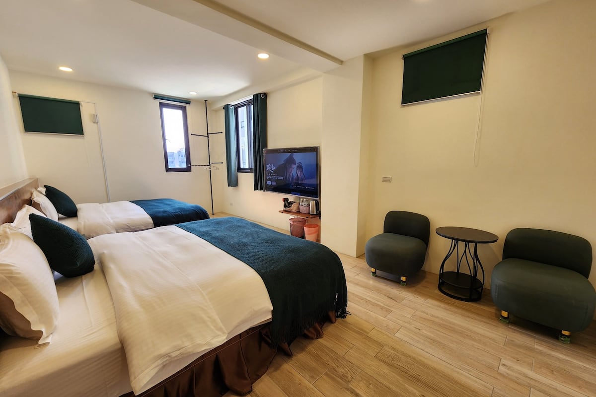 A hotel room with two beds, a TV, a small table, and two chairs.