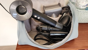 Eine Tasche mit einem Haartrockner, einem Staubsauger und einer Wasserflasche.