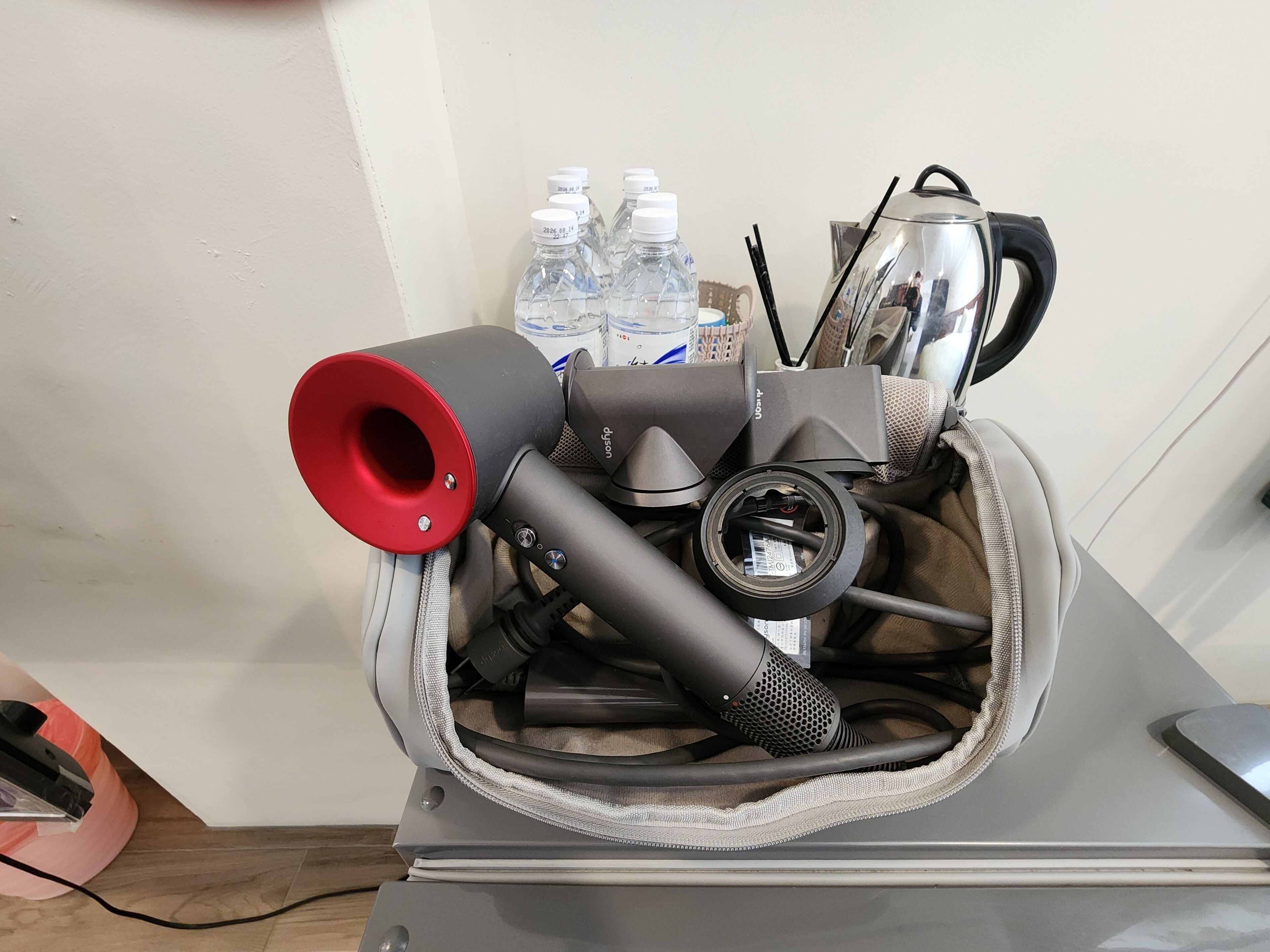 A bag containing a hairdryer, a vacuum cleaner, and a kettle.