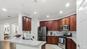 Una cocina moderna con encimeras de granito, electrodomésticos de acero inoxidable y armarios de madera.