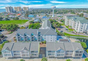 A coastal hotel with multiple-story buildings, a swimming pool, and a view of the ocean. - Charleston Village 201 (North Myrtle Beach)