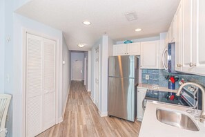 Une cuisine dotée d’un réfrigérateur en acier inoxydable, de meubles blancs et d’un plancher en bois.