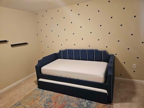 Une chambre à coucher avec un lit, une moquette à motifs et un mur décoré de motifs triangulaires noirs.