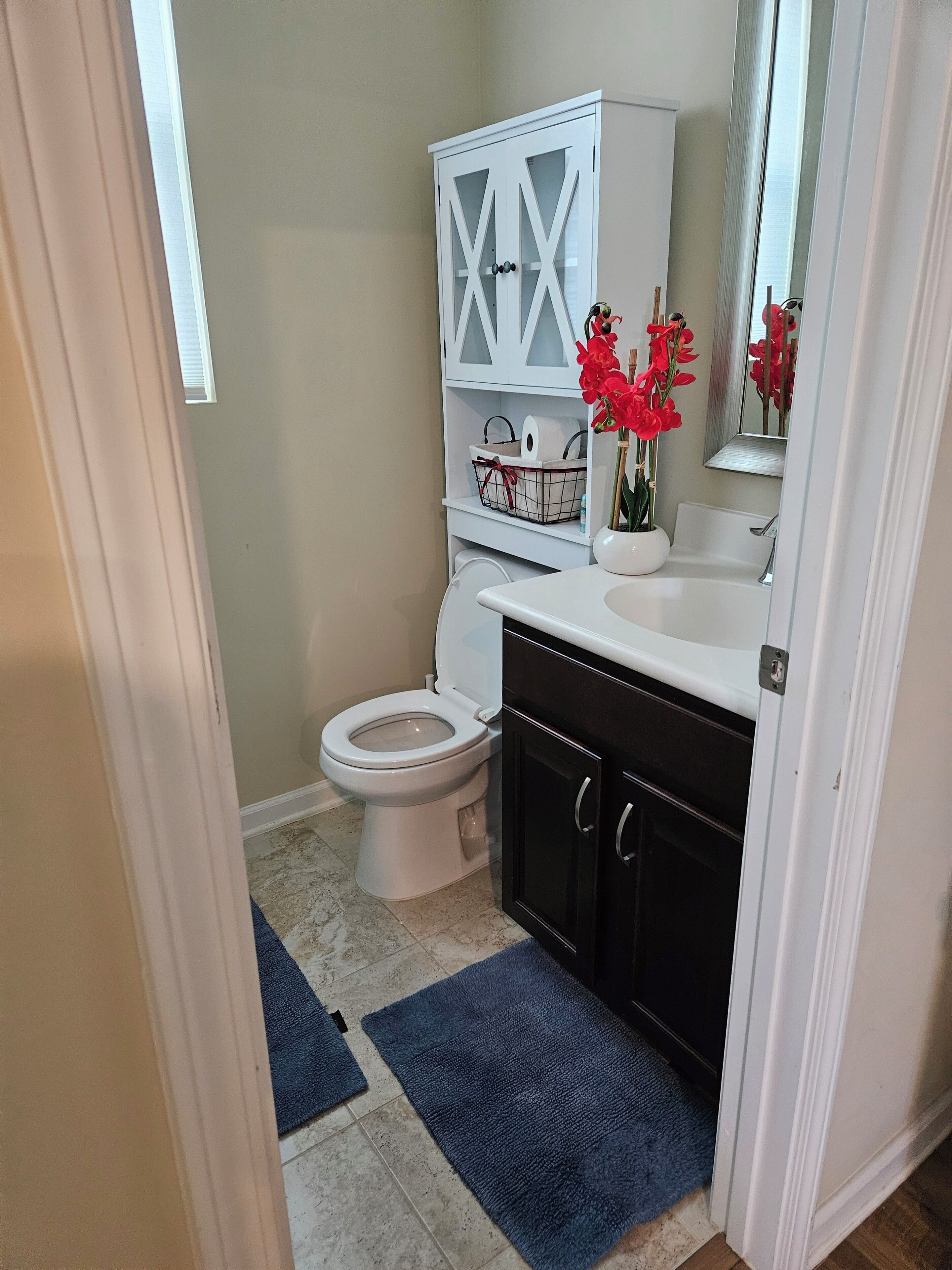 A bathroom with a white toilet, a white cabinet with a cross pattern, a sink, and a mirror.
