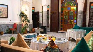 A cozy lounge area with a round table set for breakfast, comfortable seating, and a decorative door with intricate patterns. - Riad Dar Babouche (Fes)