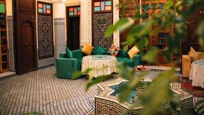 A traditional Moroccan interior with a patterned floor, green sofas, and wooden doors. - Riad Dar Babouche (Fes)